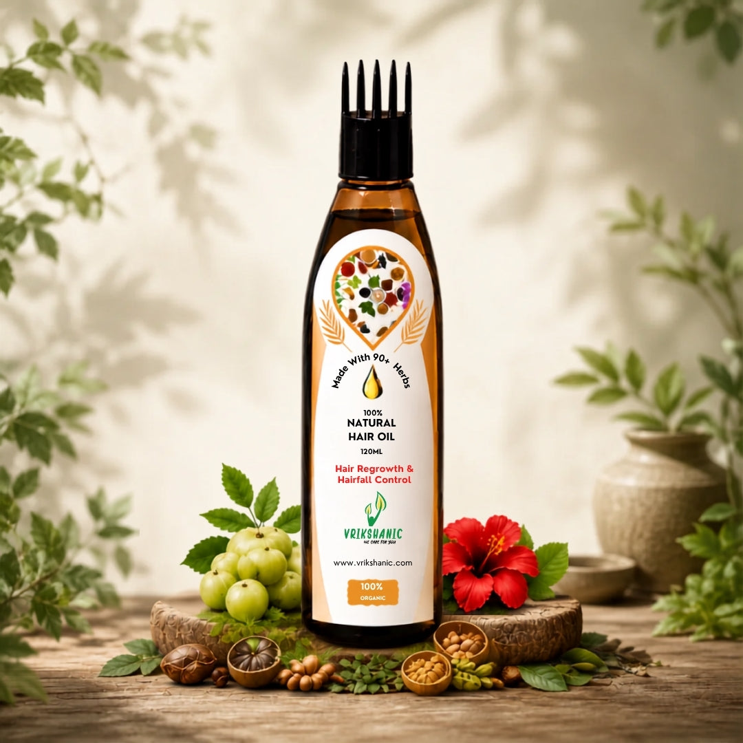 A bottle of Vritikalic 100% Natural Hair Oil stands on a rustic wooden surface surrounded by botanical elements like green grapes, a red hibiscus flower, nuts, and leaves, with soft leaf shadows on a light beige background.